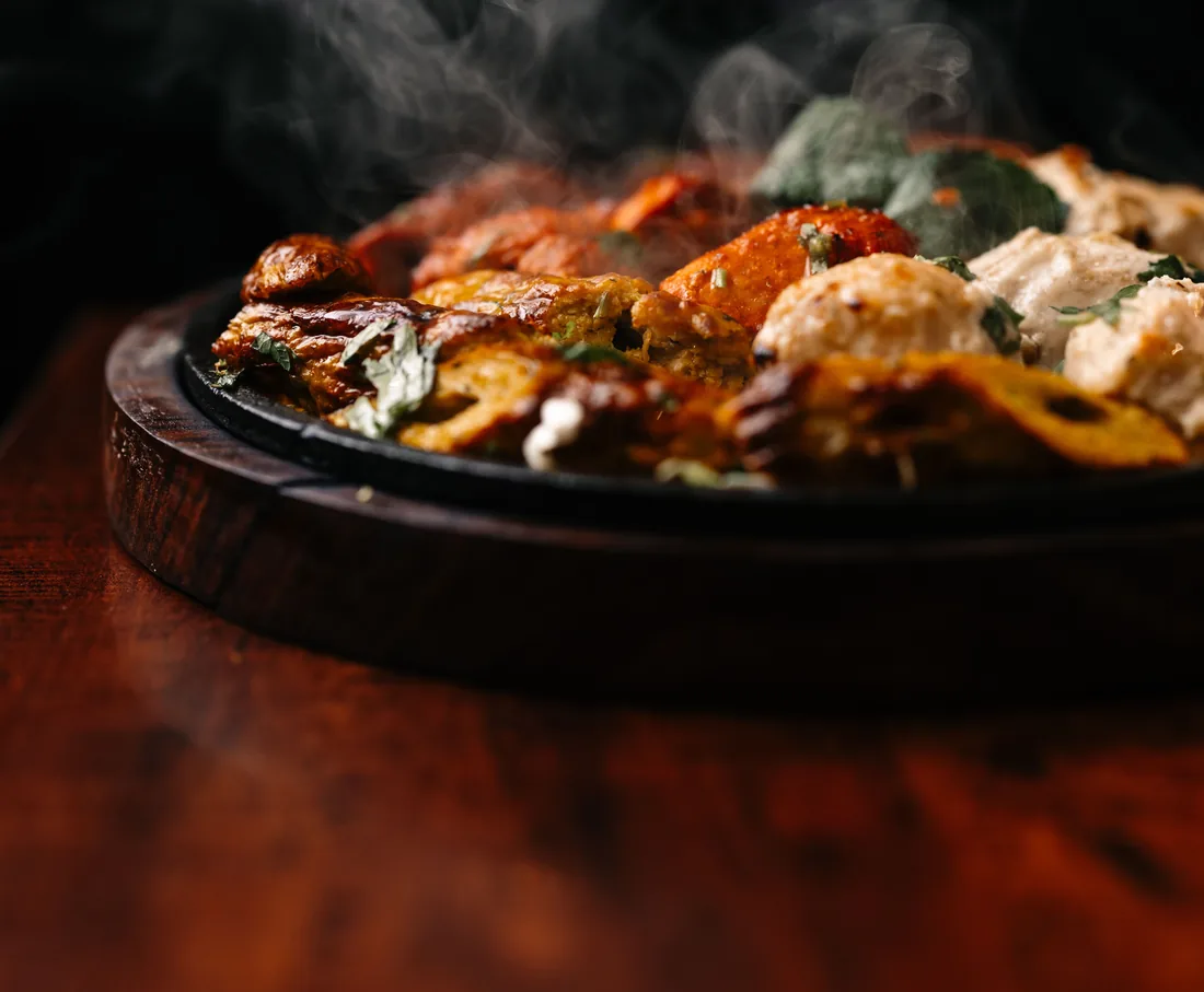Sizzling tandoori grill on a cast-iron platter, steam rising