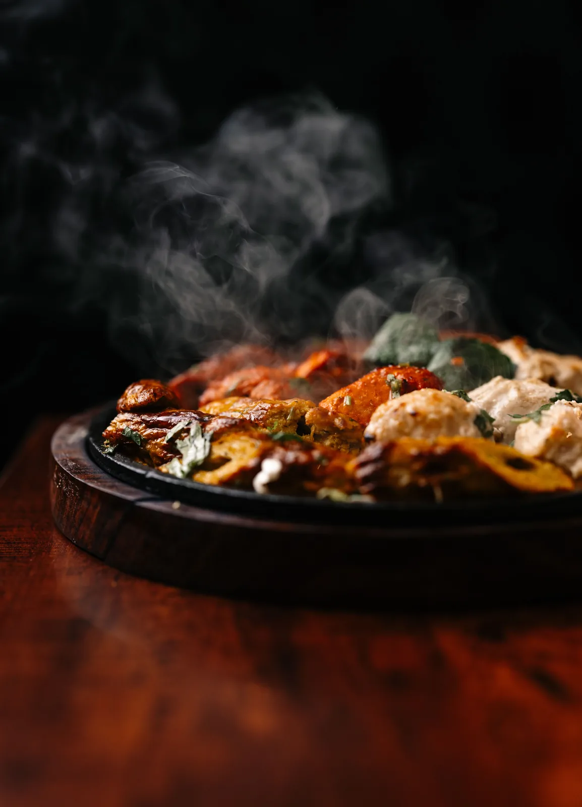 Tandoori grill sizzling on a cast-iron platter with steam rising